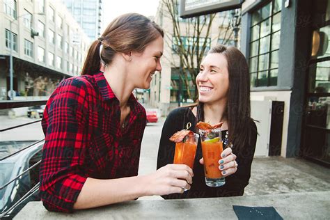 Young Beautiful Lesbian Couple Enjoying Drinks At An Outdoor Bar Together By Stocksy