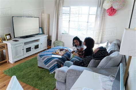 Three Female Friends Relaxing At Home Watching Tv Stock Photo Dissolve