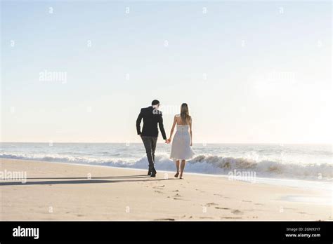 Newlywed Couple Holding Hands While Walking On Beach Stock Photo Alamy