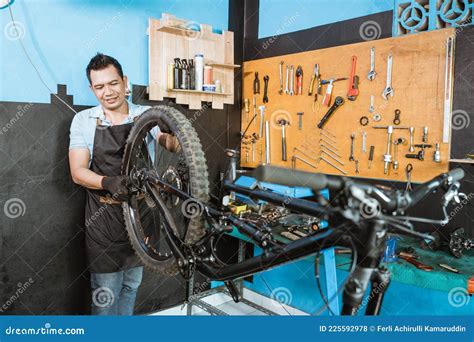 A Bicycle Mechanic In Apron Installs Wheels When Assembling A Bicycle