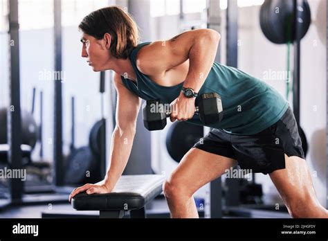 One Fit Young Caucasian Man Doing Single Arm Bent Over Rows On A Bench With Dumbbells While