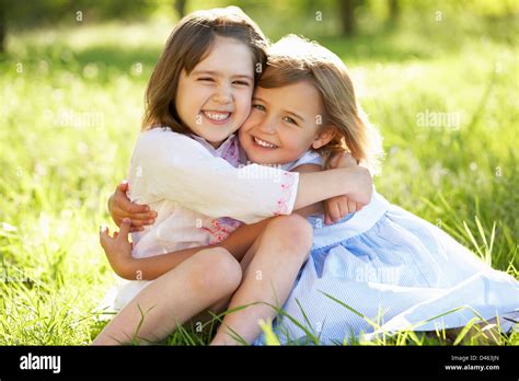 2 Young Girls Giving One Another Hug In Summer Field Stock Photo Alamy