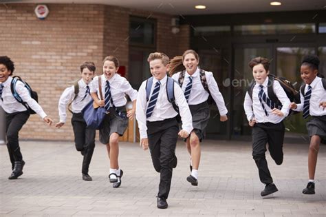 Group Of High School Students Wearing Uniform Running Out Of School