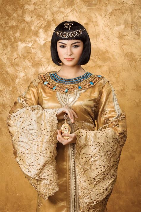 Серьезная египетская женщина как cleopatra с большими пальцами руки вверх показывать на золотой