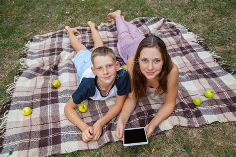 Young Sister And Brother Lying Down And Work With Tablet ⬇ Stock Photo
