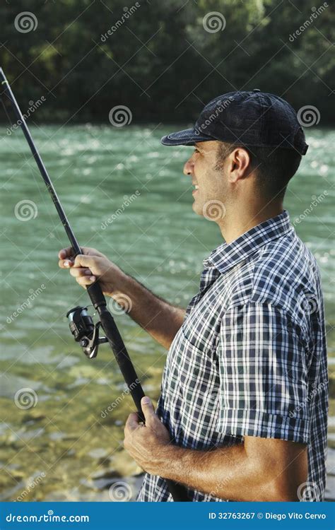 Fisherman Standing Near River And Holding Fishing Rod Stock Image