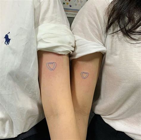 Two People With Matching Tattoos On Their Arms
