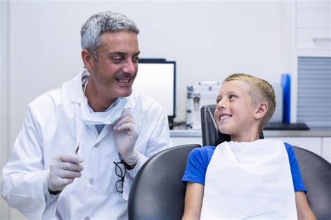 Dentista Sonriente Que Habla Con El Paciente Joven Imagen De Archivo