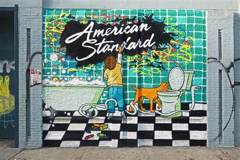 Brooklyn Street Artist Painting Exterior Mural To Prevent Vandalism In NYC