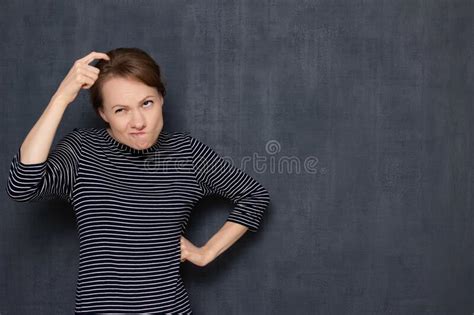 Portrait Of Funny Focused Puzzled Woman Scratching Head With Finger