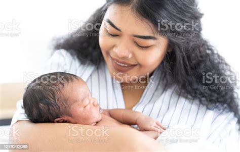 African American Mother Smiling And Holding Cute Newborn Baby On Her