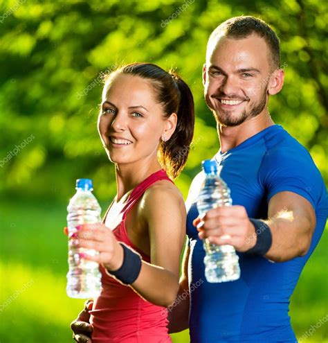 Man And Woman Drinking Water From Bottle After Fitness