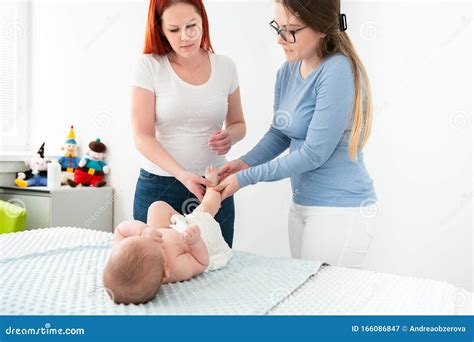Female Massage Therapist Teaching Young Mother How To Massage Her