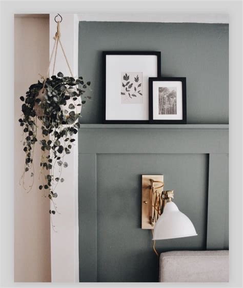 A Green Wall With Pictures On It And A White Lamp Hanging From The Side