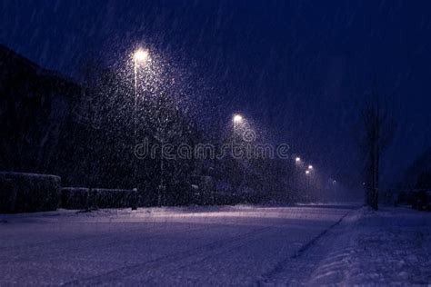 A Wide Night Portrait Of A Snowy Street With Snow Flakes Still Falling