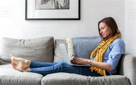 Side View Of Woman Using Laptop Computer While Sitting On Sofa In