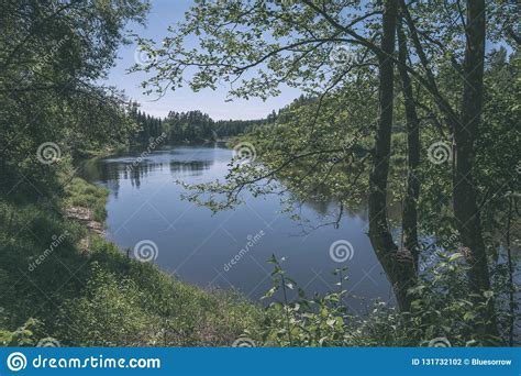 Calm River With Reflections Of Trees In Water In Bright Green Foliage