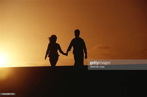 Couple Holding Hands Walking Into Sunset High Res Stock Photo Getty