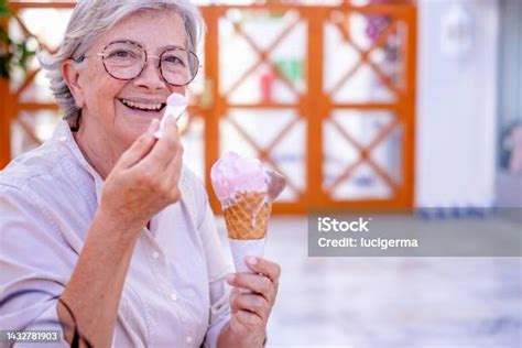 Wanita Senior Cantik Yang Bahagia Duduk Di Luar Ruangan Di Bangku Makan Kerucut Es Krim Stroberi