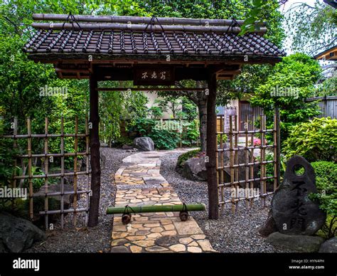 Entrance To Traditional Japanese Garden With Stone Path And Tile Roofed