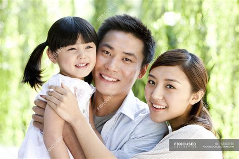 Happy Chinese Parents Carrying Daughter In Park Daylight Woman Stock Photo