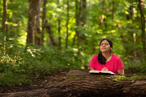 hispanic woman meditating on her bible reading in forest preserve — brilliant perspectives