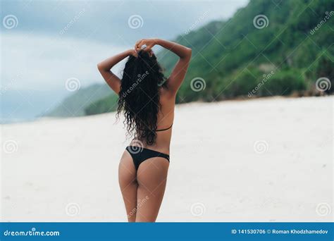 Backside View Of Dark Skined Girl With Booty In Bikini Resting On Deserted Sandy Beach Stock
