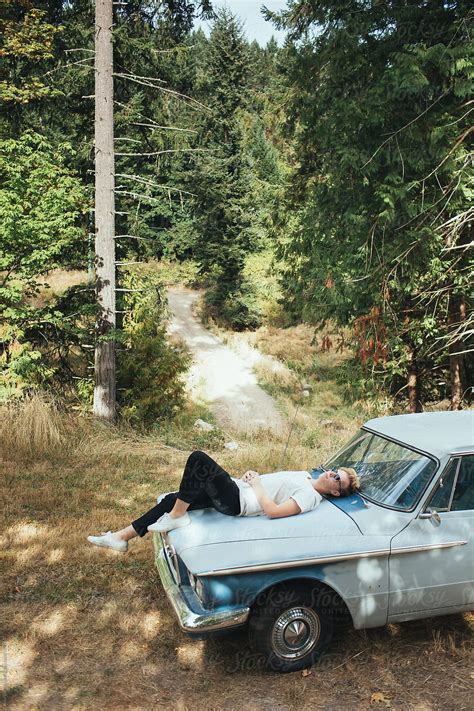 A Teenager Lying On The Hood Of His Blue Car By Stocksy Contributor