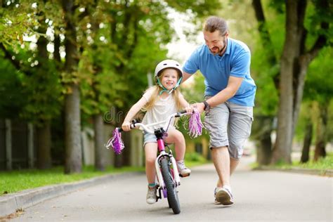 Padre Feliz Que Enseña A Su Pequeña Hija A Montar Una Bicicleta Niño