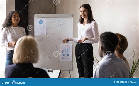 Two Diverse Business Coaches Giving Flip Chart Presentation At Meeting