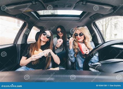 Three Girls Driving In A Car And Having Fun Eating Fast Food In Travel