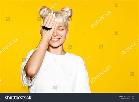 Pretty Young Smiling Woman Having Fun With Fake Eyelash On Yellow