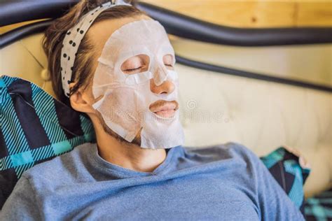 Young Man Doing Facial Mask Sheet Beauty And Skin Care Concept Stock