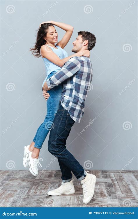Man Picking Up And Hugging His Girlfriend Over Gray Bakground Stock