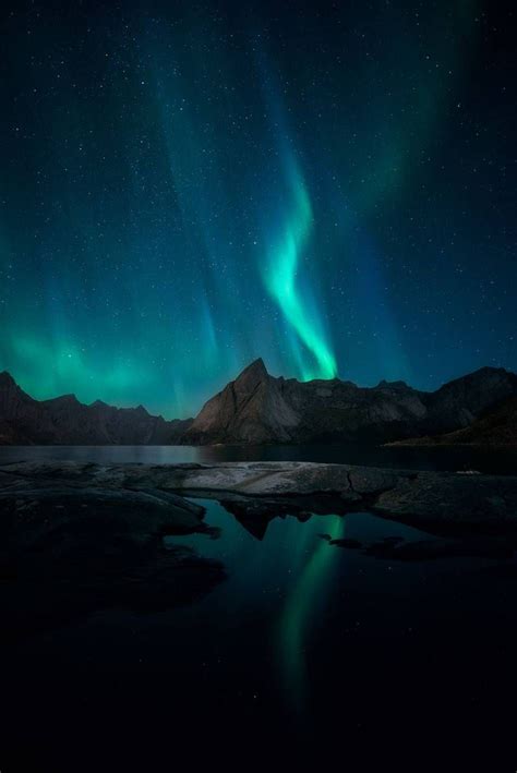 The Northern Lights Shine Brightly Over Mountains And Water