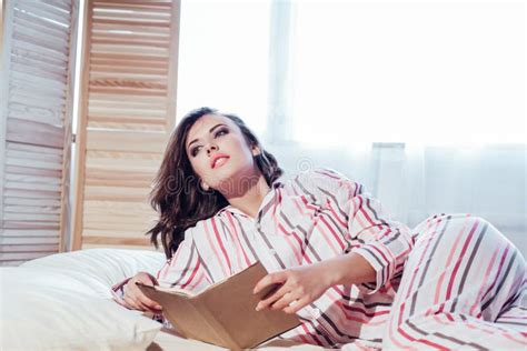 Girl In Pajamas Lying On The Bed And Reading A Book Stock Image Image