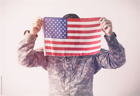 Military Man Holding Up United States Flag By Stocksy Contributor