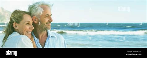Happy Couple Hugging On The Beach Looking Out To Sea Stock Photo Alamy