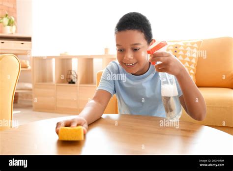 Cute Little African American Boy Cleaning Table With Sponge In Living