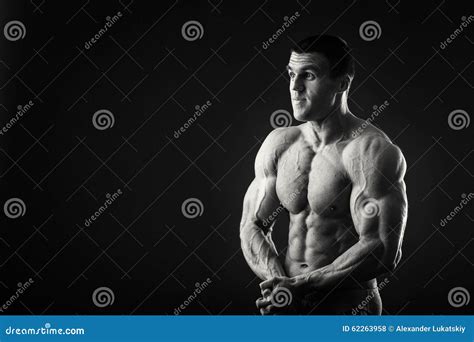 Muscular Athlete Demonstrates His Muscles Under Load On A Dark