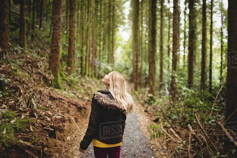 Beautiful Blonde Woman Walking On Road Surrounded By Forest Stock