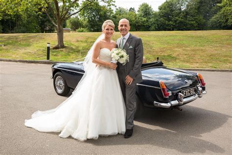 a bride and groom standing in front of a classic car