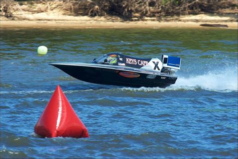 A Speed Boat Speeds Through The Water Near An Orange Cone