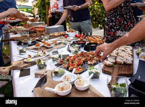 Outdoor Garden Party With Buffet Table Full Of Canapes People Serving