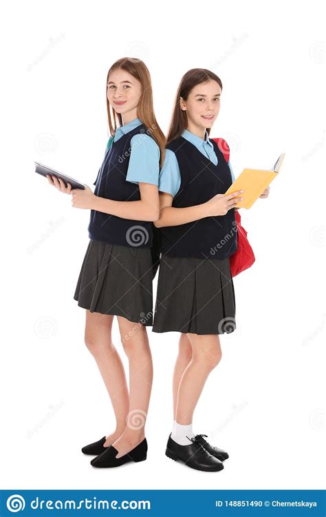 Full Length Portrait Of Teenage Girls In School Uniform With Books On