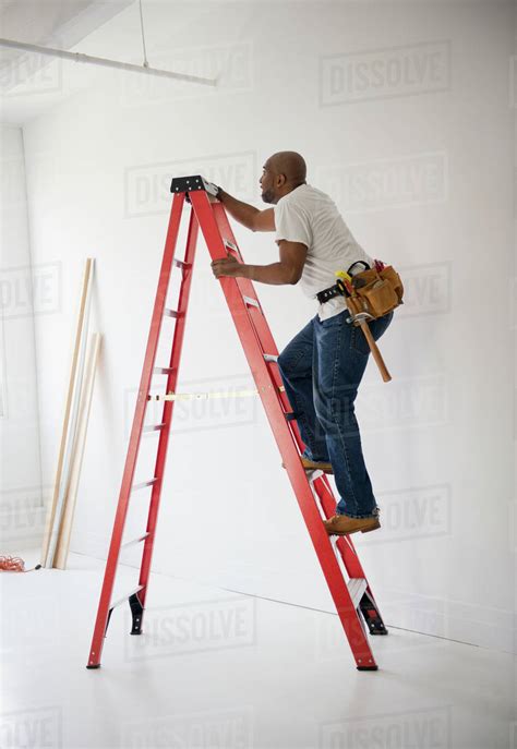African American Construction Worker Climbing Ladder Stock Photo