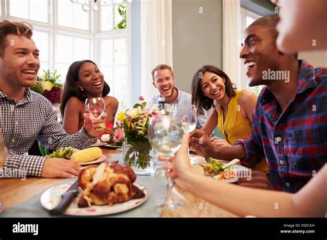 Friends At Home Sitting Around Table For Dinner Party Stock Photo Alamy