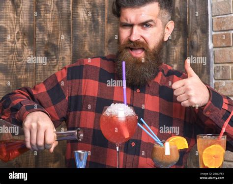 hipster enjoy drink and thumbs up barman with beard and grimace on face drinks out of glass