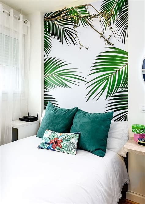 A tropical bedroom with tropical bedding, a wicker pendant lamp, potted plants and an abstract artwork. 25 Tropical Wallpaper Ideas with Greenery and Colorful Summer Charm | Tropical bedrooms ...