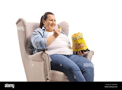 Chubby Woman Sitting In An Armchair And Eating Tortilla Chips Isolated On White Background Stock